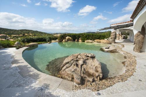 a swimming pool with a rock in the water at Hotel Pulicinu in Baja Sardinia