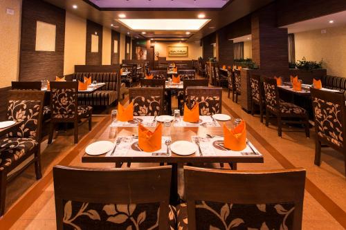 a restaurant with tables and chairs with orange napkins on them at Clinton Park Inn in Velānganni