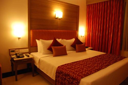 a hotel room with a bed and a red curtain at Clinton Park Inn in Velānganni