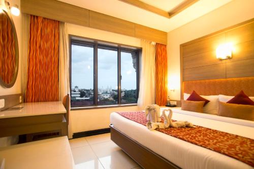 a hotel room with a bed and a window at Clinton Park Inn in Velankanni