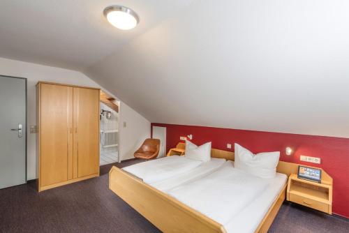 a bedroom with a large bed and a red wall at Landgasthof Ochsen in Sinzheim