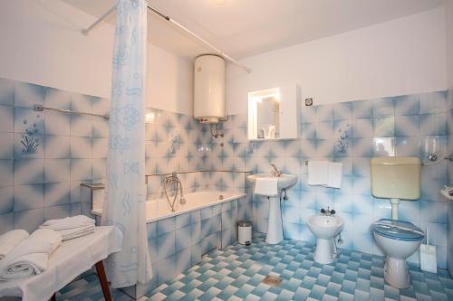 Baño azul con bañera, aseo y lavamanos en Apartment Puh, en Pula
