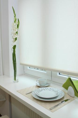 a table with a plate and a vase of flowers at Glam House Apartments in Poznań