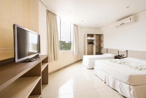 Una habitación de hotel con dos camas y un televisor de pantalla plana. en Hotel Brasil, en Penha