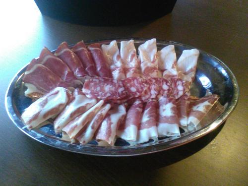 a plate of bacon and other food on a table at All'Antica Ruggine in Alseno