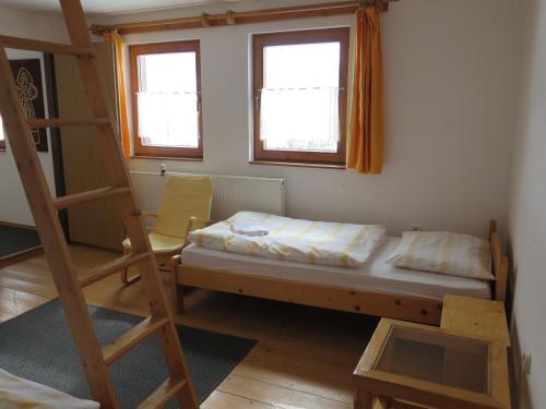 ein Schlafzimmer mit einem Bett, einer Leiter und zwei Fenstern in der Unterkunft Zubrovica in Telgárt