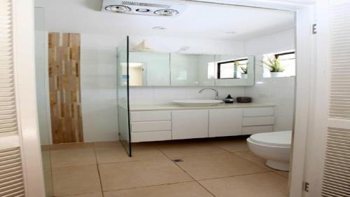 a white bathroom with a toilet and a sink at Mermaid Beach House in Gold Coast