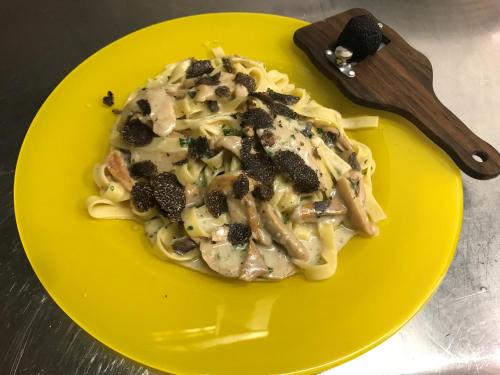 a yellow plate of pasta with mushrooms and sauce at Hotel Ski Austria St.Christoph a.A. in Sankt Christoph am Arlberg