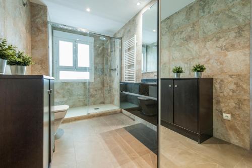 a bathroom with a toilet and a glass shower at Apartamento Plaza de Castilla II - Urbano con Estilo y Funcional in Madrid