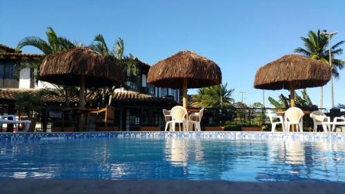 a resort with a swimming pool with chairs and umbrellas at Pousada dos Veleiros in Nova Almeida