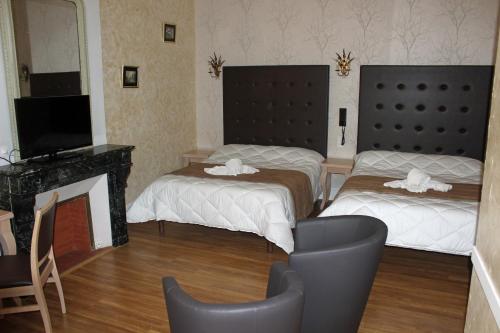 a room with two beds and a tv and a fireplace at Hotel restaurant MARTINEZ in Balaruc-les-Bains