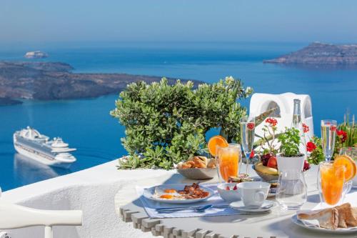 a table with a breakfast of fruit and orange juice at Mill Houses New Elegant Suites in Firostefani