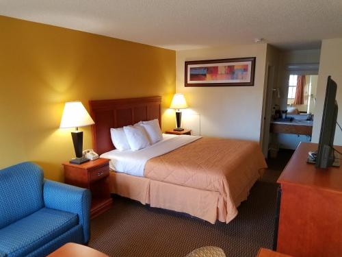 Habitación de hotel con cama y silla azul en Sylvania Inn-Sylvania,Statesboro, GA-Georgia Southern Univ GSU, en Sylvania