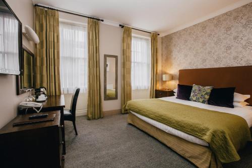 a hotel room with a bed and a desk and window at The Sun Hotel & Bar in Lancaster