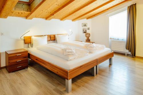 duże łóżko w sypialni z drewnianym sufitem w obiekcie Edelweiss Flora Sura w mieście Flims