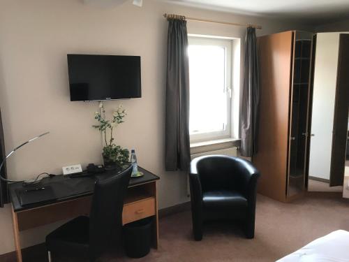 a hotel room with a desk and a chair and a television at Hotel am Maibaum in Neuenrade