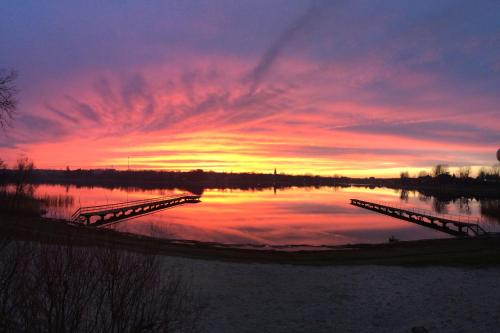 a sunset over a body of water with a bridge at Neptun in Międzychód