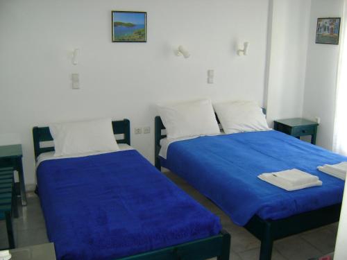 two beds with blue sheets in a room at La Fontana in Naxos Chora