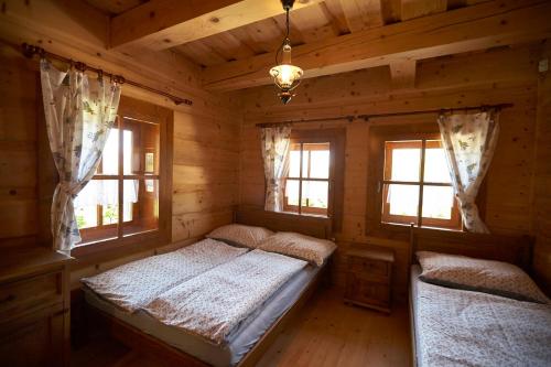 a bedroom in a log cabin with a bed and windows at Chata u strýka Joža in Terchová