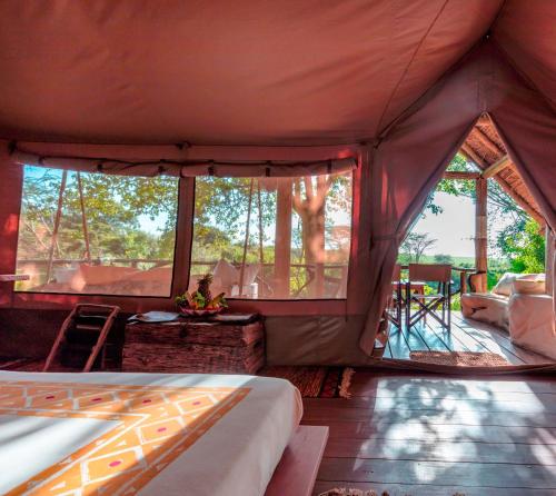 uma tenda com uma cama, uma mesa e cadeiras em Basecamp Masai Mara em Talek