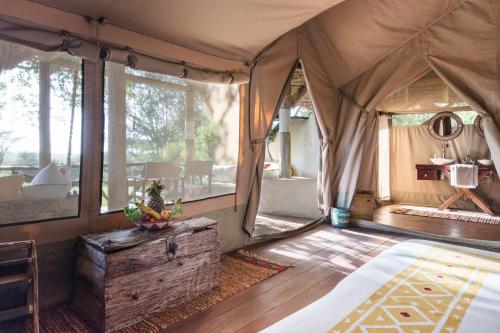TalekにあるBasecamp Masai Maraのウッドフロアのテント付きのベッドルーム1室