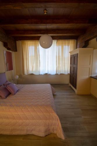 a bedroom with a bed and a large window at Agriturismo Poderi Zunino in Ponti