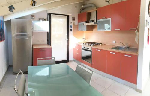 a kitchen with red cabinets and a glass table at Attico with swimming pool in Lenno