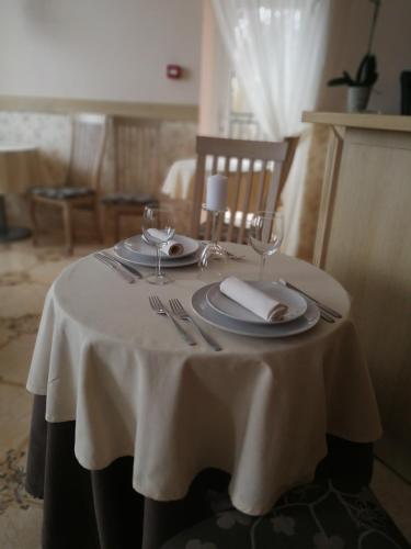 a table with a white table cloth and plates and wine glasses at Hotel Angelas in Utena