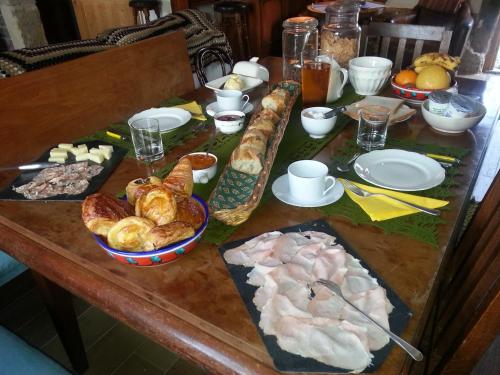 a wooden table with bread and pastries on it at B&B - Le Clos aux Masques in Saint-Pierre-Azif