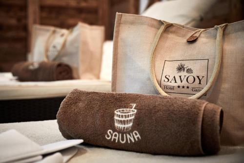 a towel on a table with a bag on a bed at Hotel Garni Savoy - new opening in Castelrotto