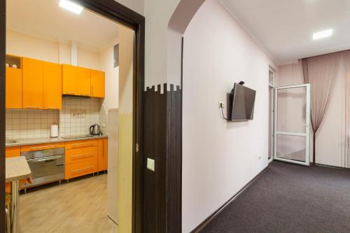 a kitchen with orange cabinets and a tv on a wall at Lux Apart Lviv apartments in Lviv