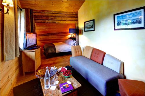 a living room with a couch and a bed at Hôtel La Ferme du Chozal, Chalet de tradition in Hauteluce