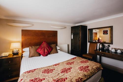 a bedroom with a large bed with red pillows at The Sun Hotel & Bar in Lancaster