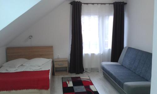 a bedroom with a bed and a couch and a window at Pensiunea Melinda in Praid
