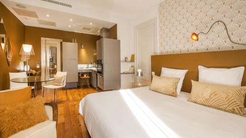 a bedroom with a large bed and a kitchen at MiHotel Gailleton in Lyon