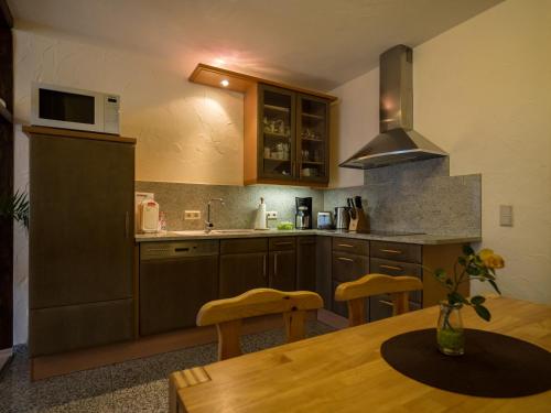 a kitchen with wooden cabinets and a table and a microwave at Ferienwohnung Meiselbach in Erfurt