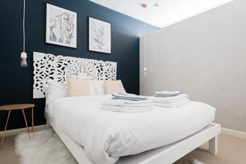 a bedroom with a white bed with a blue wall at The Paddington Studio - Cool & Stylish 1BDR Mews in London