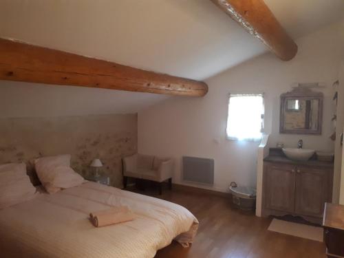 een slaapkamer met een groot bed en een wastafel. bij Mas de la Frigoule in Le Pouget