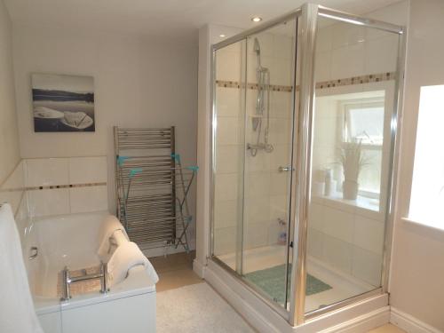 a bathroom with a shower and a bath tub at Seapinks Cottage in Portland