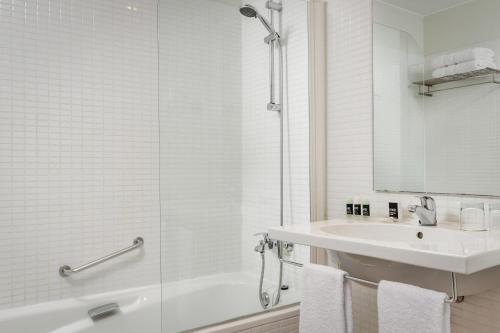 La salle de bains blanche est pourvue d'un lavabo et d'une douche. dans l'établissement Hotel Exe Barcelona Gate, à Sant Joan Despí