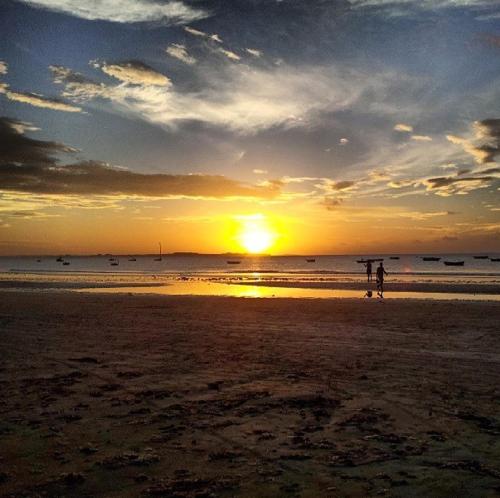 two people walking on the beach at sunset at Pousada Aconchego in Mundaú