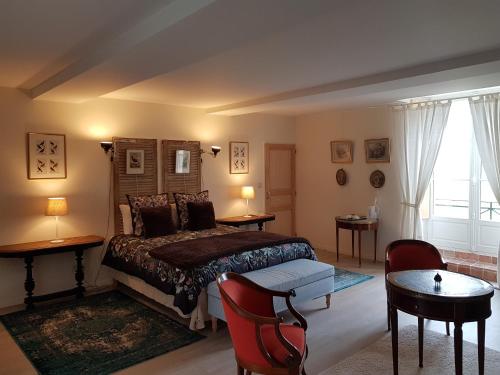 a bedroom with a bed and a table and chairs at Le Manoir du Ribardon in Neuvy-au-Houlme