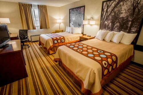 a hotel room with two beds and a television at Super 8 by Wyndham State College in State College