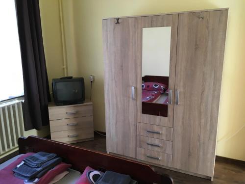 a large wooden cabinet with a mirror and a tv at Fitt Magánszálláshely in Sásd