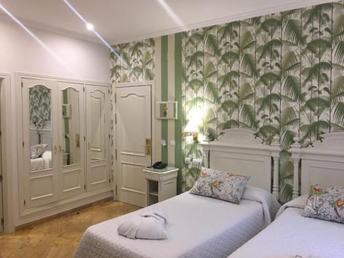 a bedroom with two beds and green and white walls at Adriano Boutique Sevilla in Seville