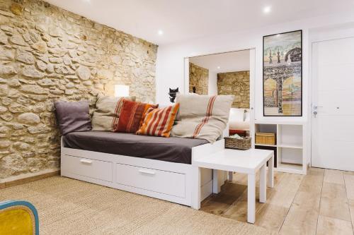 a couch in a room with a stone wall at Bravissimo Old Side Girona One, cozy apartment in Girona