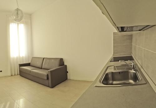 カンピョーネ・デル・ガルダにあるCampione Ora apartments by Gardadomusmeaのシンクの横にソファ付きのキッチン
