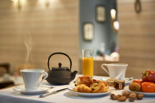 a table with cups and plates of food and coffee at Best Western Premier HBEO Bordeaux Centre in Bordeaux