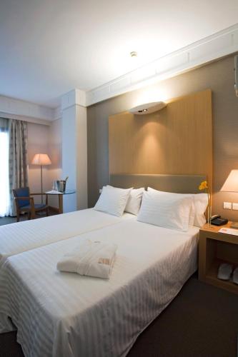 a hotel room with a large bed with a towel on it at Central Hotel in Athens