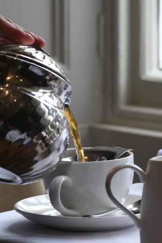 a teapot pouring coffee into a cup on a table at Cotswold House Hotel and Spa - "A Bespoke Hotel" in Chipping Campden